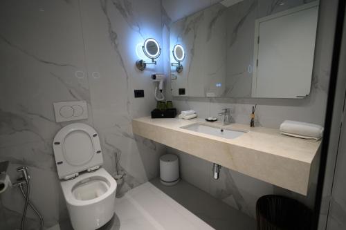 a bathroom with a toilet and a sink and a mirror at Holiday Hotel in Tirana