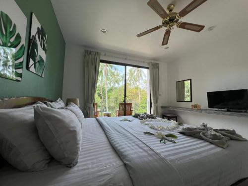 a bedroom with a white bed with a ceiling fan at Woodlawn Villas Resort in Koh Tao