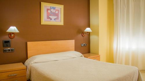 a bedroom with a bed and two lights and a picture at Hostal Meseguer in El Altet