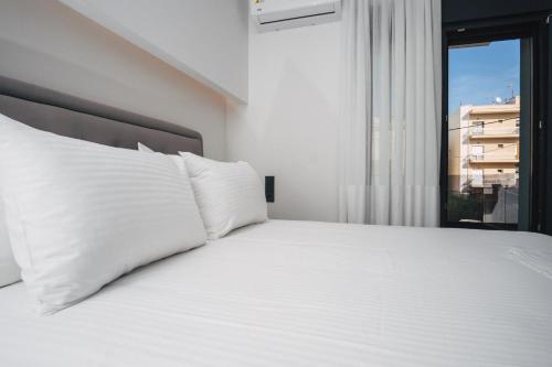 a white bed with white pillows and a window at Home Avenue in Alexandroupoli