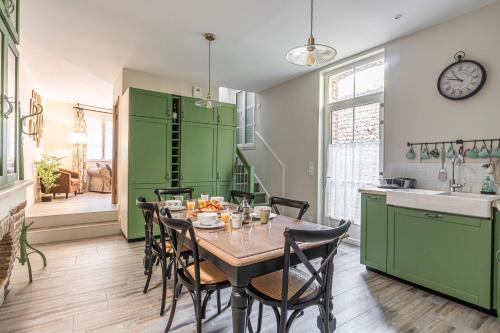 une cuisine avec des placards verts et une table avec des chaises dans l'établissement La Grive - 400m Plage - Confort, à Étretat