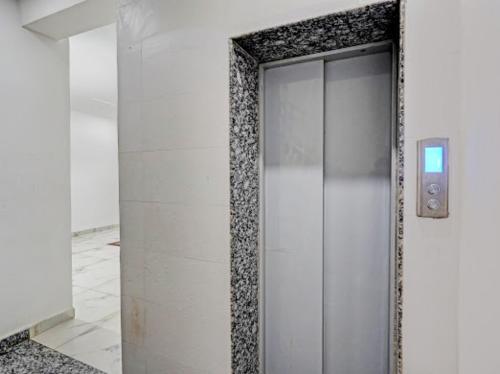 a glass elevator door in a white room at Akshay dream stay in Gurgaon