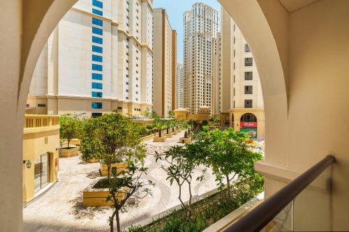 a view of a city with tall buildings and trees at Beautiful 2BR & 4BR Apartments on JBR Beach, Walking Distance to Bluewaters Island - By Sunkissed Holiday Homes in Dubai
