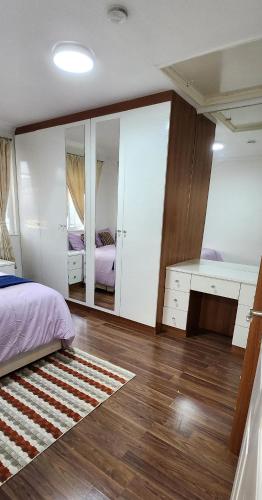 a bedroom with a bed and a desk and a mirror at Amalia's Guest House in Abbey Wood