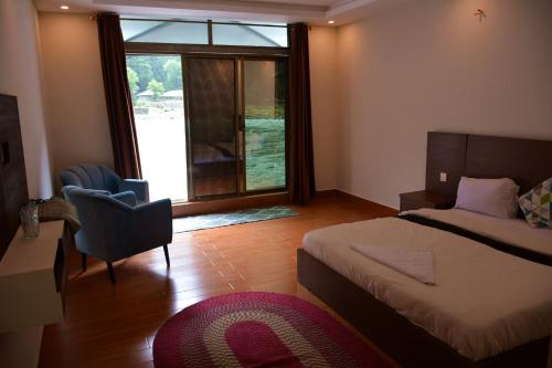 a bedroom with a bed and a chair and a window at Keran Retreat in Upper Neelun
