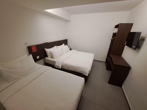 a hotel room with two beds and a shelf at Hotel Al Abraar in Melaka