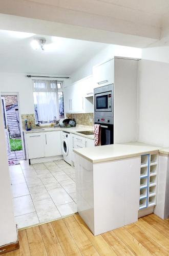 a kitchen with white cabinets and a white counter top at Amalia's Guest House in Abbey Wood