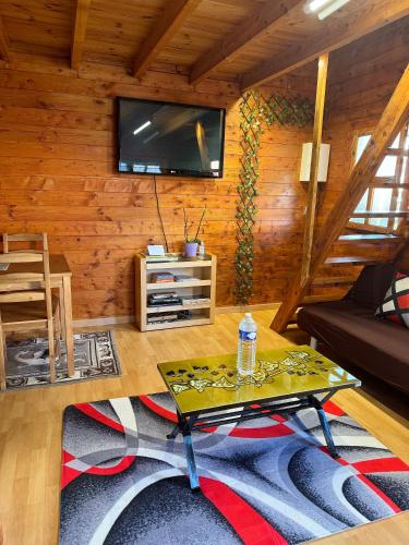 un salon avec une table et une télévision au mur dans l'établissement Cozy cottage Paris Suburb!, à Bobigny