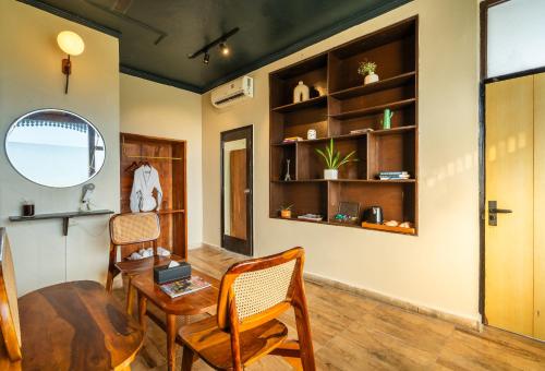 a living room with a table and two chairs and a table and a mirror at Minimalist One Hauz Khas Village in New Delhi