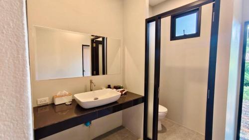 a bathroom with a sink and a mirror at Mon Tresor Garden มง เทร ซอ in Amphoe Sawang Daen Din