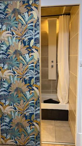 La salle de bains est pourvue d'une douche et de papier peint bleu et blanc. dans l'établissement Studio Gare Dijon centre, à Dijon