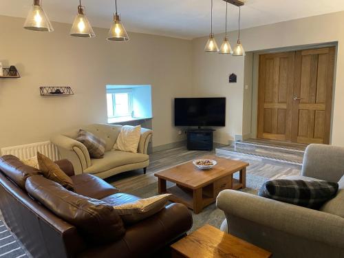 a living room with couches and a tv at Grange Cottage in Ballynoe