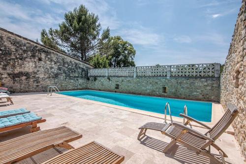 une piscine avec deux chaises et un mur en pierre dans l'établissement Grand gîte de caractère 25 personnes piscine, à Ners