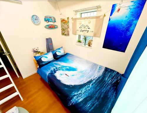 a bed in a room with a wave painted on the wall at レベアス片瀬江ノ島WEST 片瀬江ノ島 鎌倉 ビーチまで2分 駅徒歩6分 無料Wifi in Katase