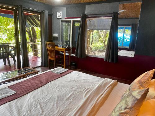 a bedroom with a bed and a table and windows at Samyama Retreat in Cola