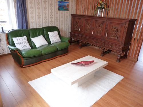 a living room with a green couch and a coffee table at Gite les bons amis in Plombières