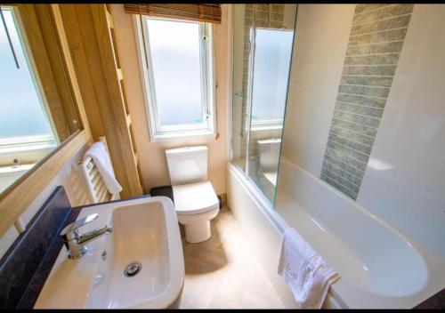 a bathroom with a sink and a toilet and a tub at MP778 - 2B Lodge - Parkdean - Camber Sands in Camber