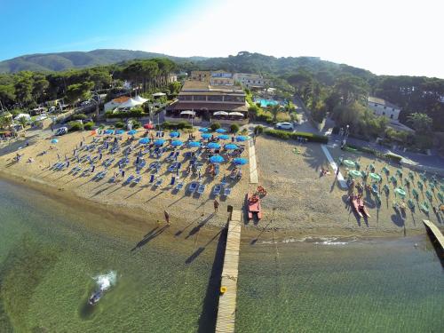 a group of people on a beach with chairs and umbrellas at Frank's Hotel in Capoliveri