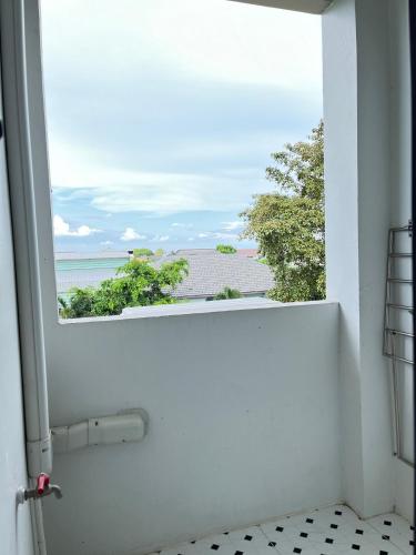 a bathroom with a window with a view of the ocean at The Gun Hotel in Surin
