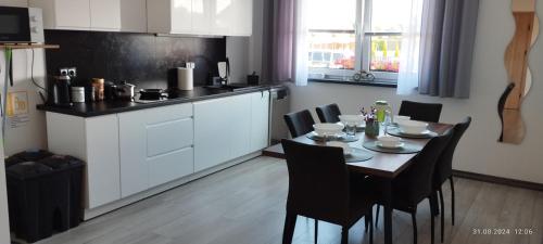 Una cocina con una mesa y sillas en una cocina. en Biały Dom, en Sarbinowo
