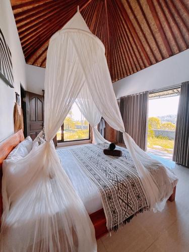 a bedroom with a bed with white mosquito netting at Batur cottage in Kubupenlokan