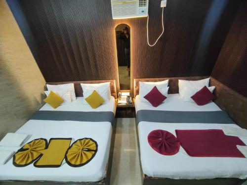 two beds with colorful pillows on them in a room at The Vacation Villa in Agra