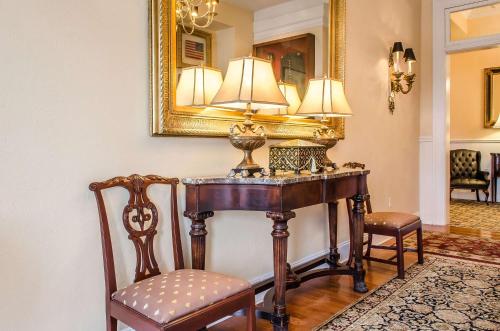 a table with a lamp and two chairs and a mirror at The Federal Pointe Inn Gettysburg, an Ascend Collection Hotel in Gettysburg