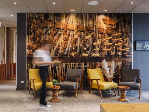 a person walking in a lobby with a wall of pots and pans at ibis Lyon Carre De Soie in Vaulx-en-Velin