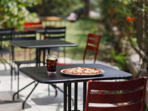 a pizza sitting on a table with a drink at ibis Lyon Carre De Soie in Vaulx-en-Velin