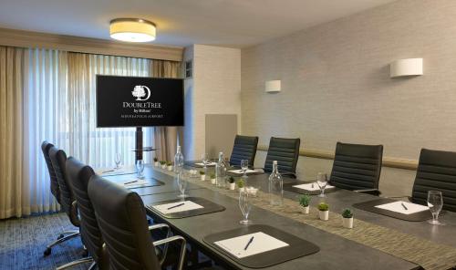a conference room with a long table with chairs and a screen at DoubleTree by Hilton Minneapolis Airport, MN in Bloomington