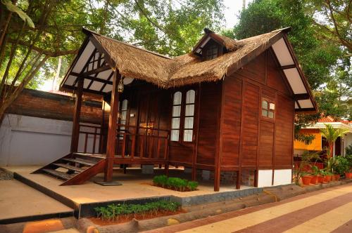 a small wooden house with a straw roof at Raja Park Beach Resort in Varkala