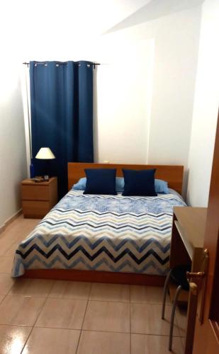 a bedroom with a bed with a blue curtain at MELROSE PLACE 2 Dormitorios y Piscina en Vecindario in Vecindario