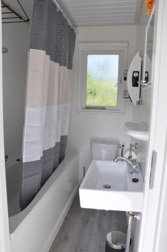 a white bathroom with a sink and a shower at Chalet Christine in Petten