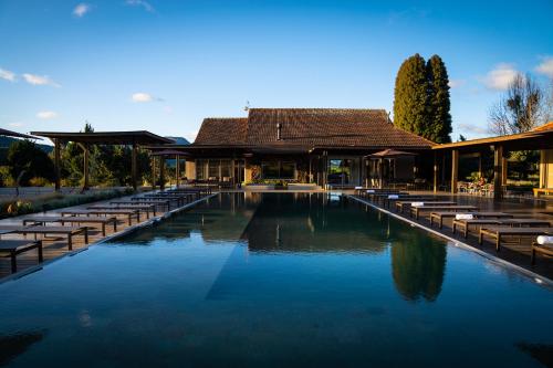 a swimming pool with benches and a building at Pousada Fazenda Bom Retiro - Vinícola Thera in Bom Retiro