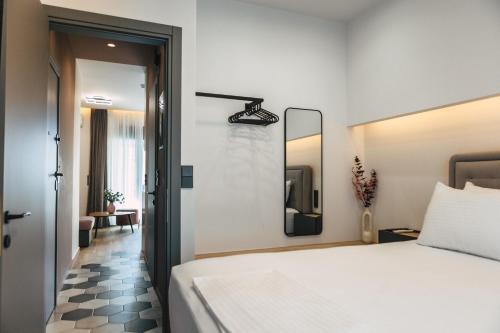 a bedroom with a white bed and a mirror at Home Avenue in Alexandroupoli