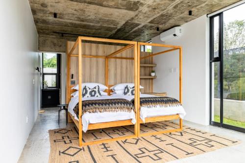 a bedroom with a canopy bed in a room with windows at SALT Luxury Guest Suite Plett in Plettenberg Bay