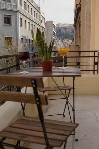 a table with two glasses of wine and a plant on a balcony at My Athens House in Athens