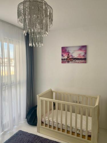 a white nursery with a crib and a chandelier at White Luxury Apartment in Sibiu