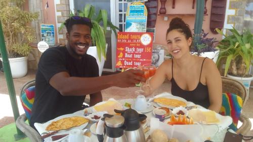 a man and woman sitting at a table with a glass of wine at Residencial Cabo Verde Palace in Santa Maria