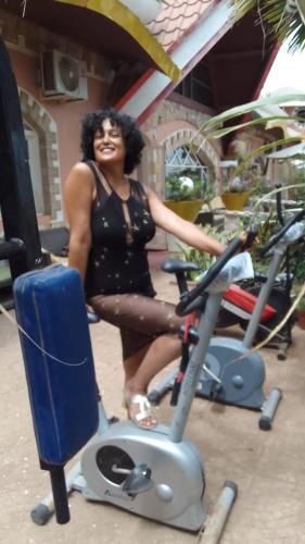 a woman is standing on a exercise bike at Residencial Cabo Verde Palace in Santa Maria