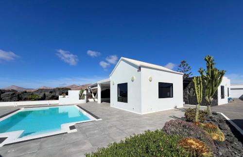 a white house with a swimming pool in a yard at Habitación de invitados Casa Lume in Tahiche