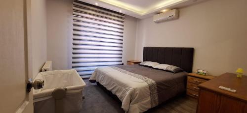 a bedroom with a bed and a window with blinds at SAKN 3 - Two Bedroom Apartment in Amman