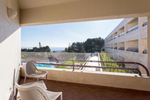 a balcony with chairs and a view of a pool at Four Points by Sheraton Sesimbra in Sesimbra