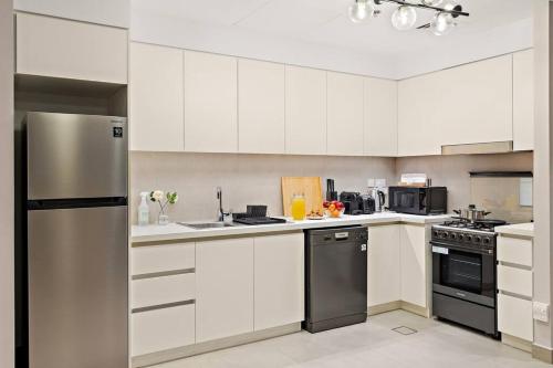 a kitchen with white cabinets and a stainless steel refrigerator at Chic 2BR Stay at Creek Horizon with Pool, Gym and Prime Dubai Location in Dubai