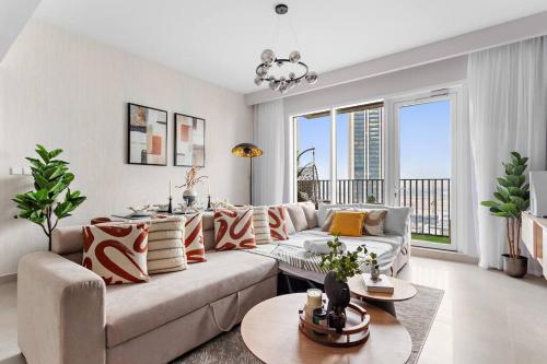 a living room with a couch and a large window at Chic 2BR Stay at Creek Horizon with Pool, Gym and Prime Dubai Location in Dubai