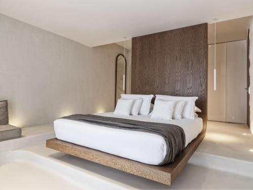 a bedroom with a large white bed with white pillows at Mykonos Earth Suites in Mýkonos City