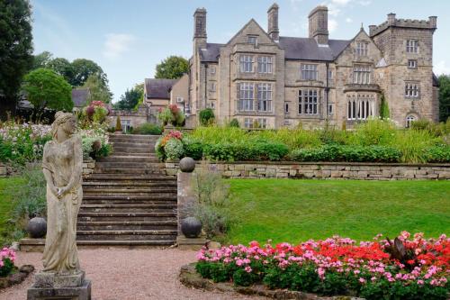 a statue in front of a house with flowers at Delta Hotels by Marriott Breadsall Priory Country Club in Derby