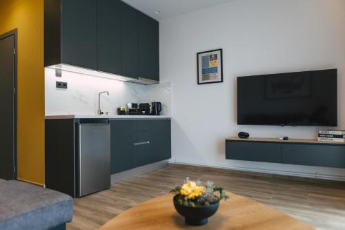 a kitchen with black cabinets and a tv on the wall at Home Avenue in Alexandroupoli