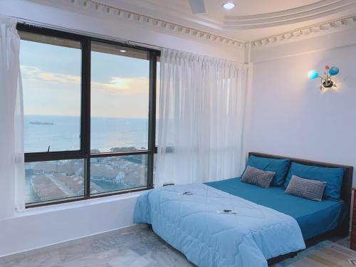 une chambre avec un lit bleu et une grande fenêtre dans l'établissement Glory Beach Duplex Ocean View - 8Pax 3BR & FREE Disney Hotstar, à Port Dickson