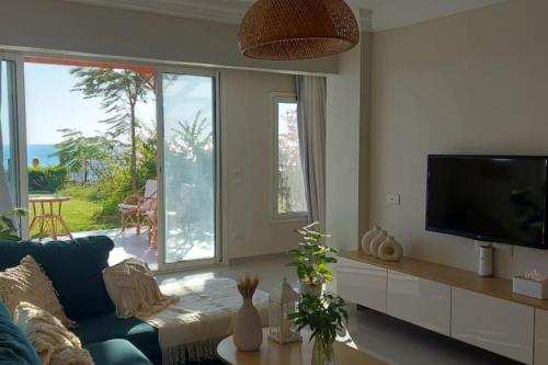 a living room with a blue couch and a tv at Luxurious beachfront chalet with spacious garden in Makman